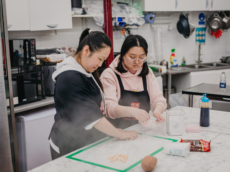 Two people wearing aprons preparing ingredients for bubble tea